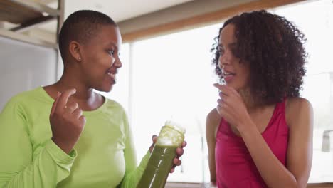 diversas amigas felices intentando una bebida saludable en casa