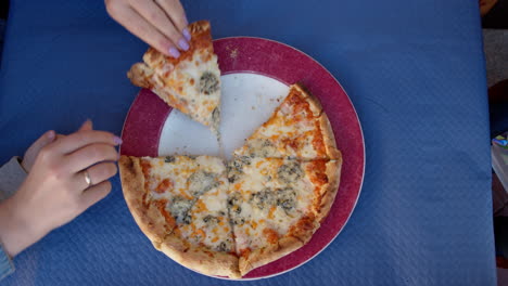 las manos tomando rebanadas de pizza del plato