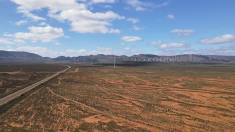 Drone-aerial-moving-left-of-renewable-energy-wind-power-farm-in-desert-country-Australia-on-a-sunny-day