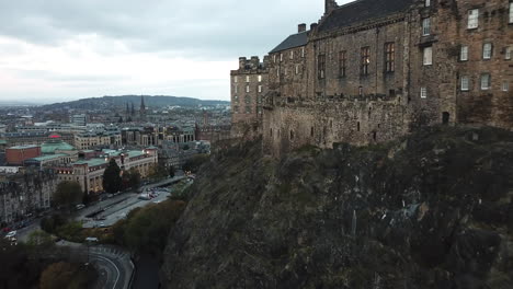 Drone-shot-panning-around-Edinburgh-Castle-on-a-dark,-cloudy-morning