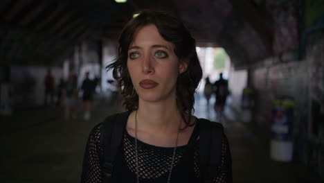 fashion portrait of young alternative style woman walking along dark underpass with graffiti covered walls on london city street uk in real time 1