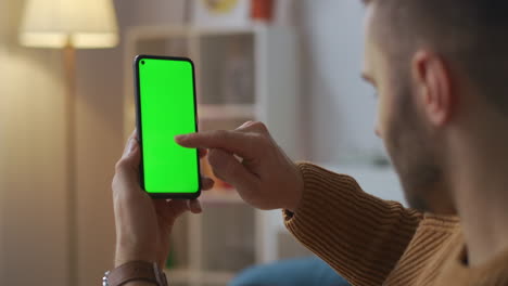 Un-Hombre-Adicto-A-Internet-Está-Usando-Un-Teléfono-Inteligente-En-Casa-Por-La-Noche-Deslizando-Y-Tocando-La-Pantalla-Verde-Y-Pasando-Tiempo-En-Aparatos-Electrónicos-Y-Redes-Sociales