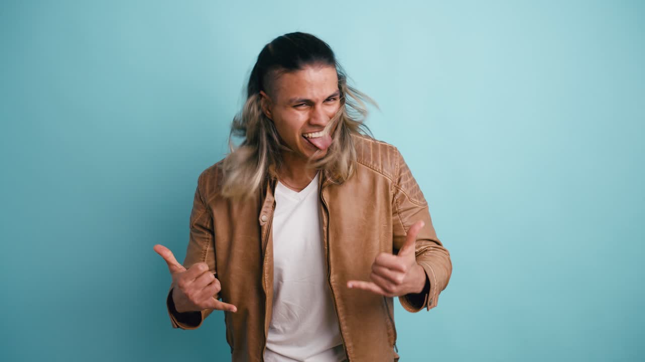 Giovane uomo energico che fa gesti rock and roll con le mani
