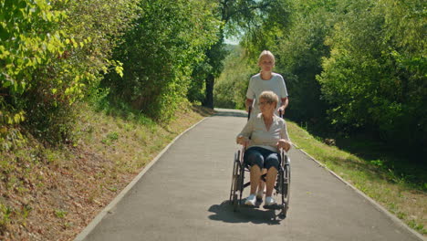 woman pushing elderly woman in wheelchair in a park