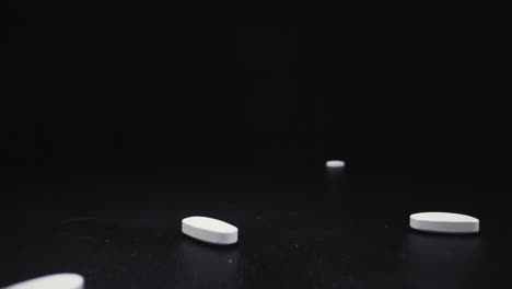 throwing numerous pills onto black surface close view