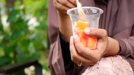 women eating papaya from a plastic take away container