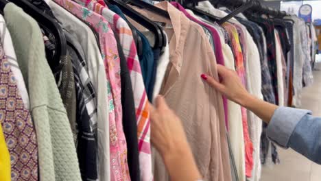 a young poor girl browses the racks of clothes in a thrift store a young poor girl browses the racks of clothes in a thrift store a young woman chooses used clothes for shopping