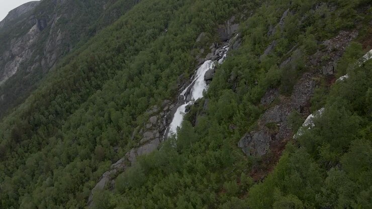 Cascata che scende lungo un pendio montano attraverso una foresta