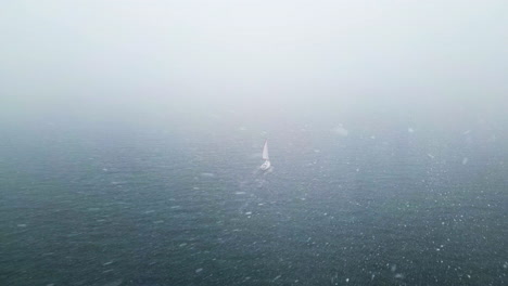 Toma-De-Drone-De-Un-Velero,-Conduciendo-A-Través-De-Un-Mar-Remoto-Y-Brumoso,-Durante-Una-Tormenta-De-Nieve.