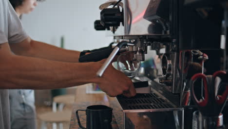 barista hands making coffee with modern coffee machine in cafeteria close up.