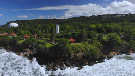 Zeitlupenwellen,-Die-In-Felsen-In-Der-Nähe-Eines-Leuchtturms-In-Puerto-Rico-Mit-Grünen-Bäumen-Hinter-Dem-Meer-Krachen