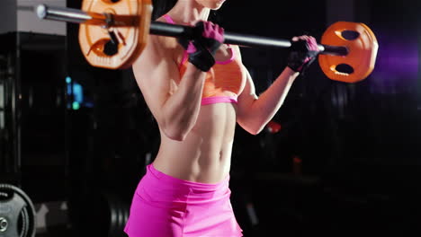 athletic woman trains muscles of the hands with a barbell female bodybuilding