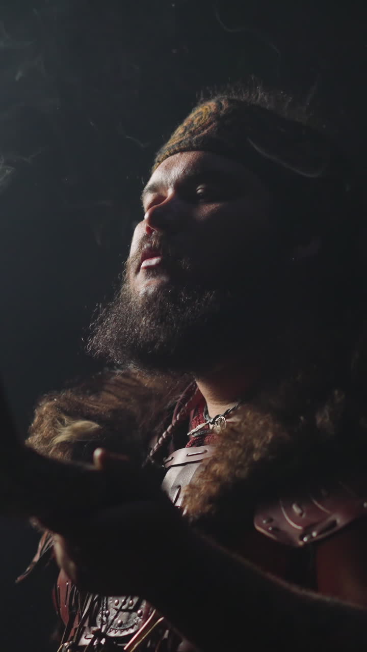 Ecstatic young shaman in Altai ethnic costume and swirling smoke on dark background slow motion. Spiritual traditions of Siberian folks