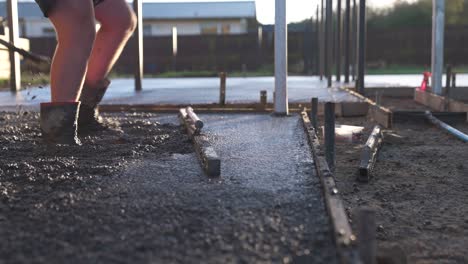 contractor smoothing fresh concrete surface of residential driveway with wooden float