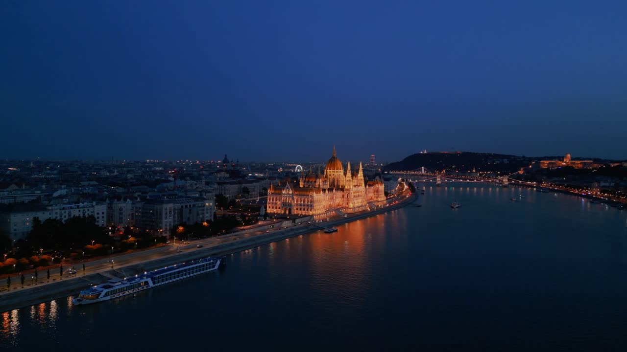 Hungarian Parliament at night reflecting in Danube River with Budapest city lights glowing