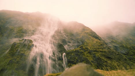 Serene-waterfall-with-clean-spring-water-flowing-down-a-cliff-with-rocks-covered-in-moss