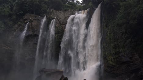 stunning view of nauyaca waterfalls, costa rica, with water cascading down a mossy cliff into a misty pool, framed by lush rainforest