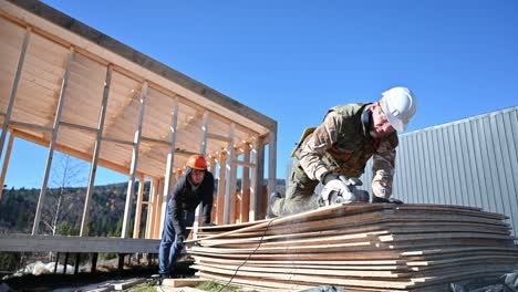 carpenter using circular saw for cutting osb board for building wooden frame house.