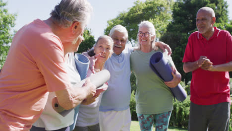 Grupo-Diverso-De-Felices-Hombres-Y-Mujeres-Mayores-Hablando-Después-De-Hacer-Ejercicio-En-Un-Jardín-Soleado,-Cámara-Lenta