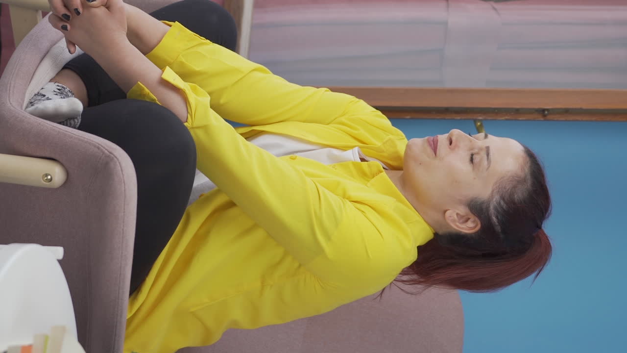 창문 앞에 있는 여자가 깊은 숨을 쉬고 눈을 감고 있는 수직 비디오입니다.