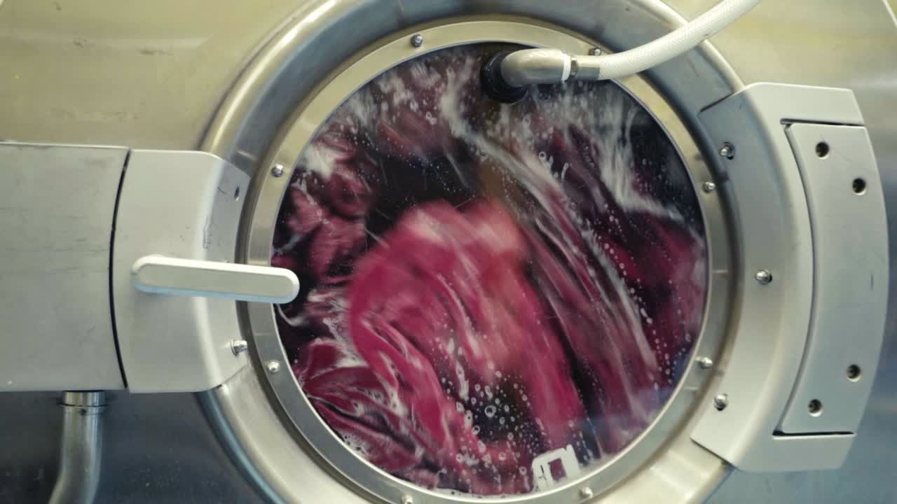 close-up view of an industrial machine washing clothes with soap and water, ensuring thorough cleaning and efficiency.