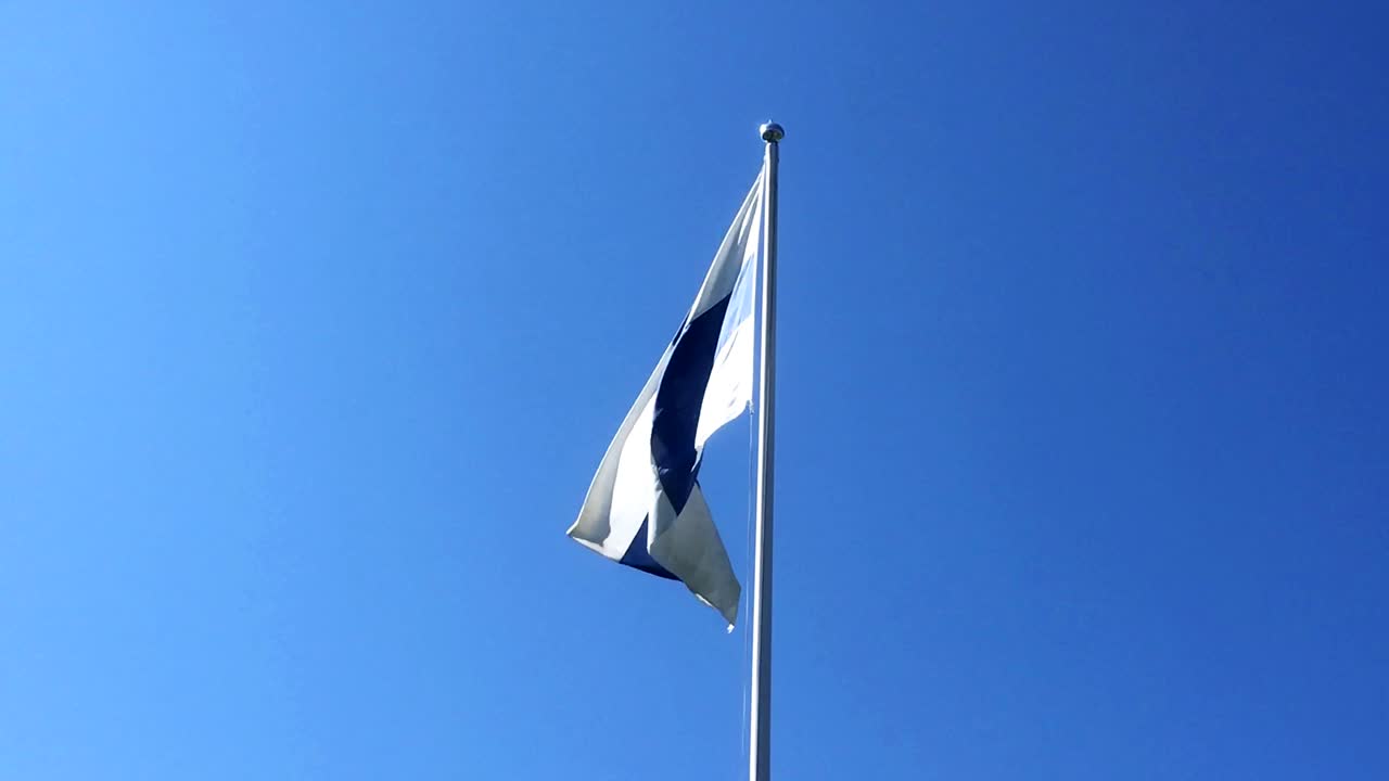 la bandera de finlandia ondeando en cámara lenta con un cielo azul claro en el fondo