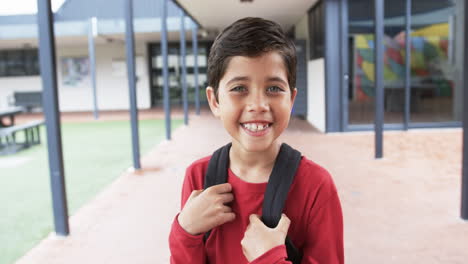 in a school courtyard, a young caucasian boy smiles brightly