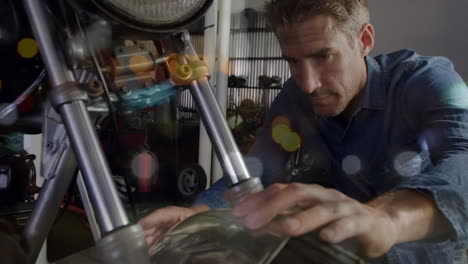 animación de luces parpadeantes sobre un mecánico caucásico que fija una motocicleta