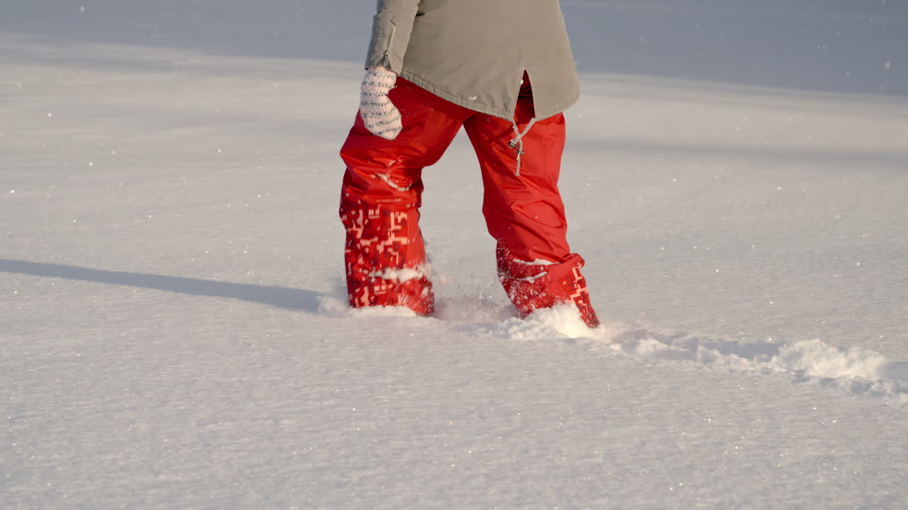 Una persona abrigada camina por nieve hasta las rodillas.