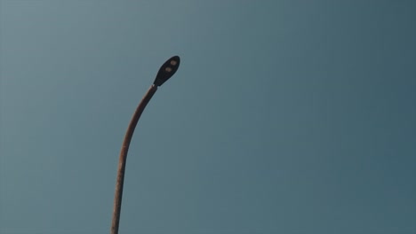Panning-shot-of-a-turned-off-steel-street-light-pole-at-twilight-with-clear-sky