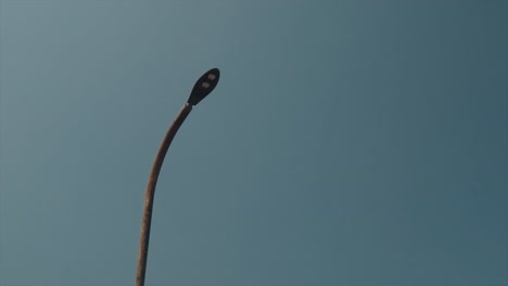 Toma-Panorámica-De-Un-Poste-De-Luz-De-Calle-De-Acero-Apagado-En-El-Crepúsculo-Con-Cielo-Despejado