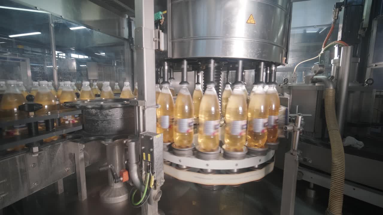 una máquina automática de llenado vierte agua o jugo en botellas de plástico en una moderna planta de bebidas
