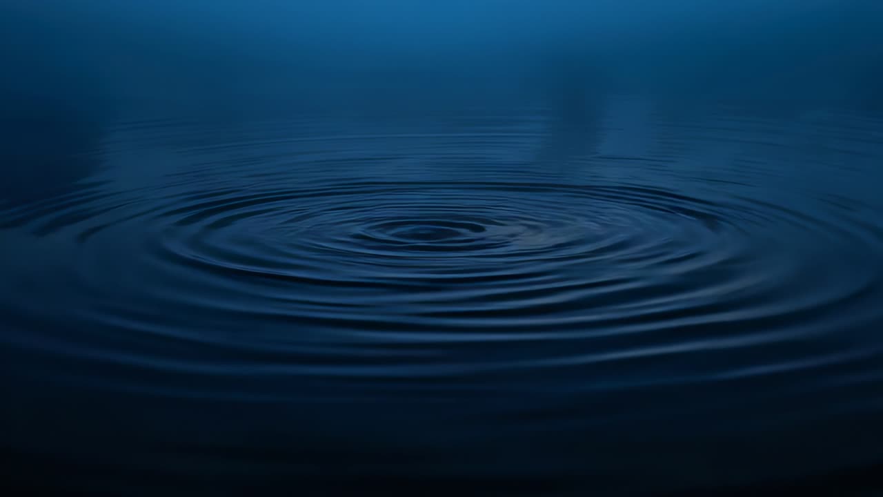 Increspature circolari che si irradiano verso l'esterno da un punto centrale su uno stagno calmo, con deboli riflessi.