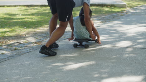 rear view of young man pushing skateboard with little girl on it