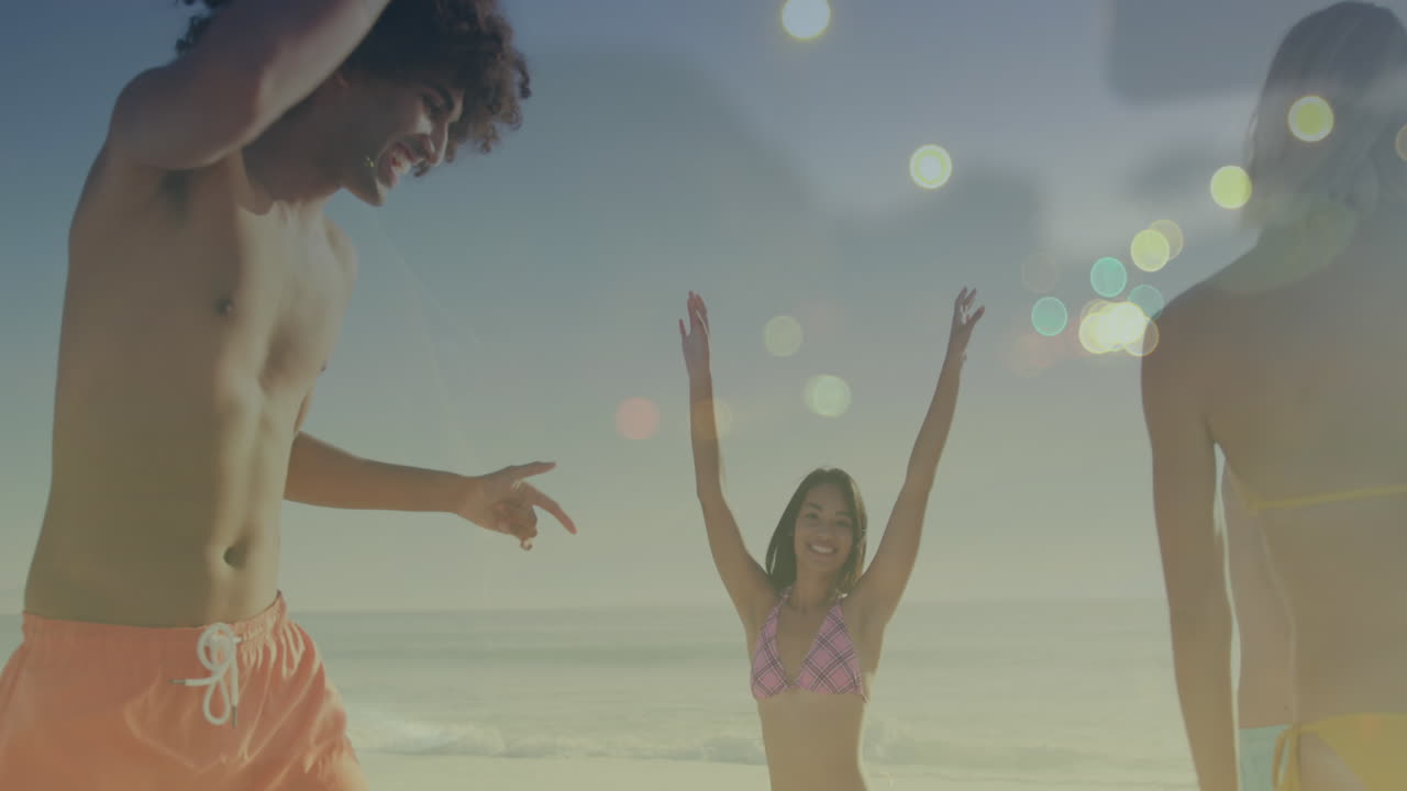animación de puntos de luz sobre felices amigos diversos bailando en la playa