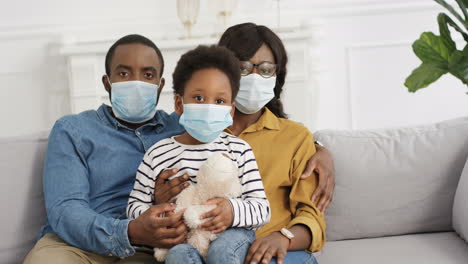 familia joven con un niño lindo con máscaras médicas en casa encerrado