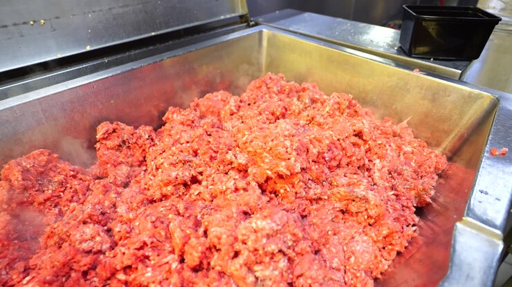 Workers hands put cooked spices into a large pot at a catering food factory