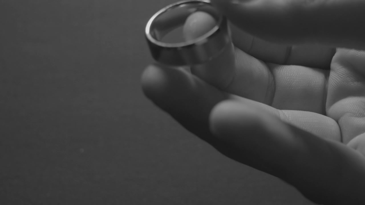 Close up look at a gold wedding band in black and white video.