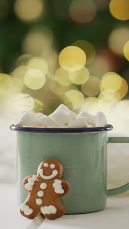 video vertical de tazas de chocolate caliente con malvaviscos sobre el árbol de navidad