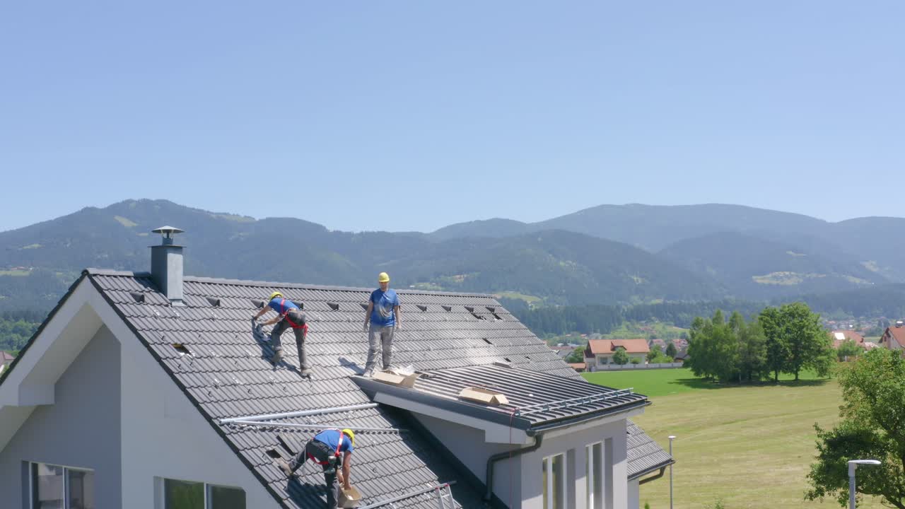 Rising aerial footage showing workers adjusting the tiles on the roof of the house for installation of solar panels. Concept of professionalism, Job, solar power