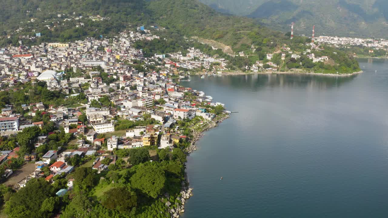 Öğle vakti Guatemala'daki Atitlan Gölü'nün kıyı şeridi boyunca evleri ve villaları gösteren drone kaydırma çekimi.