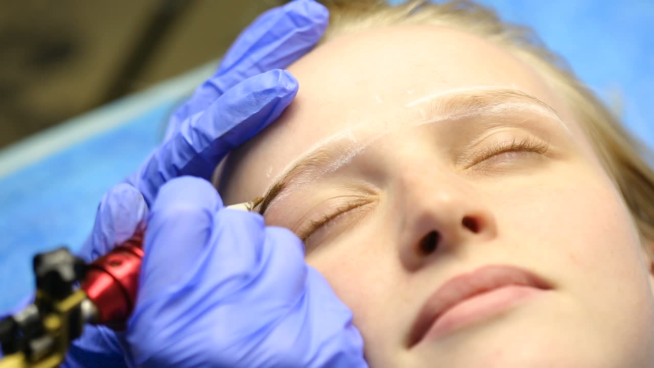 Tattooist making permanent make-up. Close up of specialist doing eyebrow tattooing for female