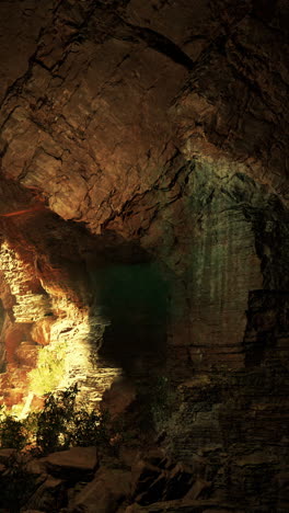 inside a dark cave, a rock formation is lit by sunlight filtering through the entrance