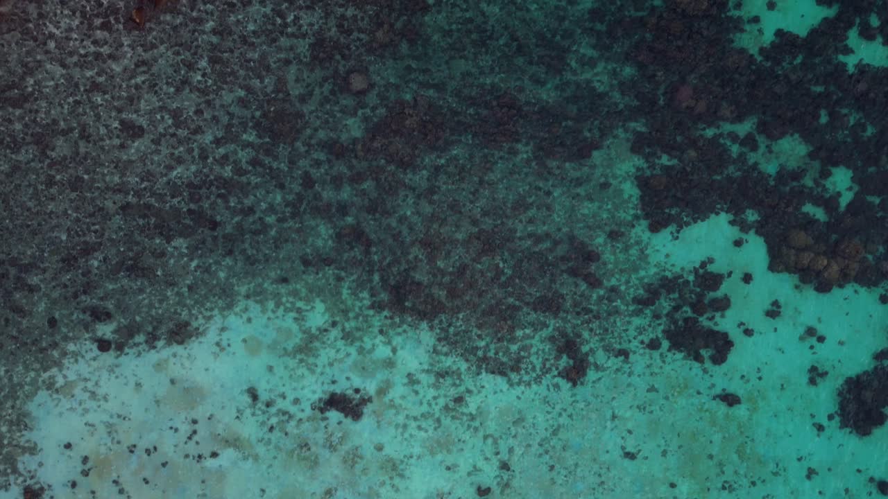 열대 섬의 아름다움, 푸른 바물과 바위가 있는 해안선을 포착하는 이 공중 사진은 울창한 절벽과 해안가에 활기찬 파란색과 초록색 색조를 보여줍니다.