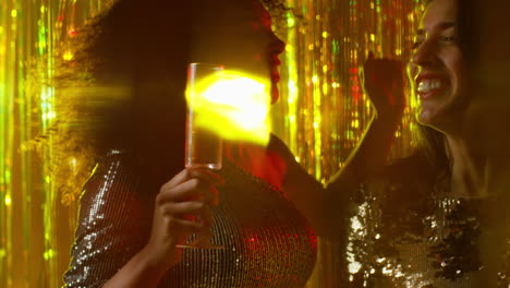 close up of two women dancing in nightclub bar or disco drinking alcohol with sparkling lights 21