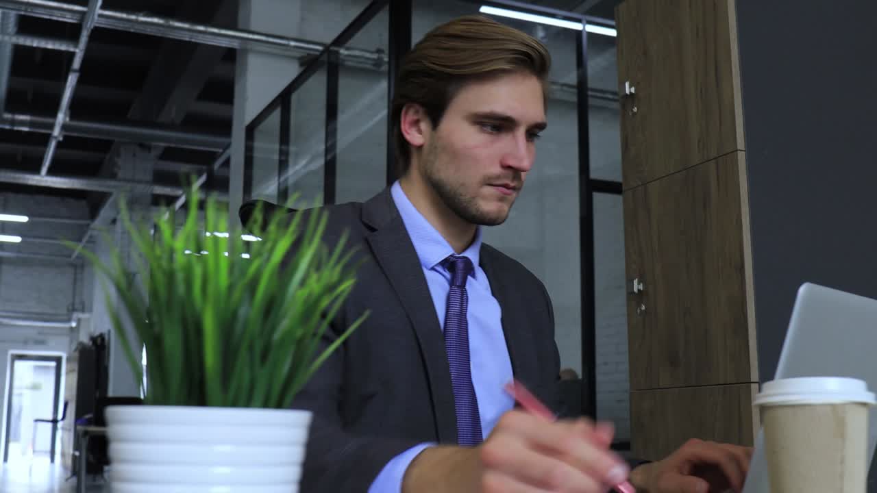 homem de negócios de fato sentado na mesa de trabalho e trabalhando em um laptop.