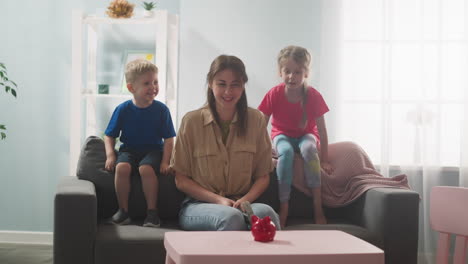 Woman-with-hammer-looks-at-children-ready-crash-piggy-bank