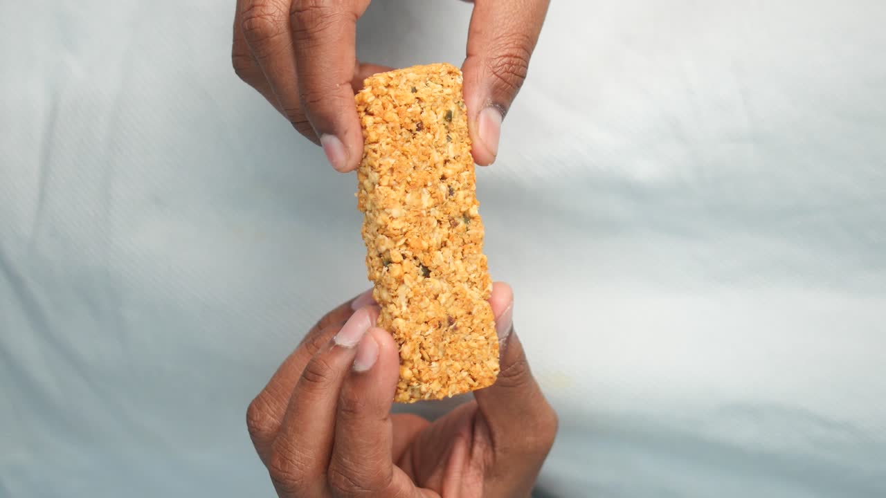 manos sosteniendo una barra de granola