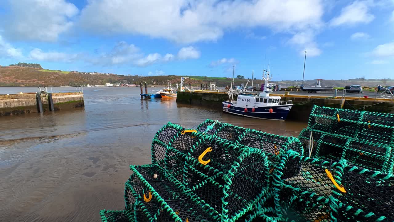 Pittoresco porto di pescatori con nasse per aragoste e barca da pesca con la bassa marea a Passage East, Waterford, Irlanda