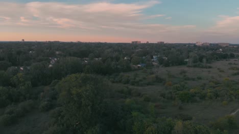 Circling-aerial-shot-of-nepean,-ontario-hovering-over-a-park-with-trees-and-buildings-of-the-city-in-the-background